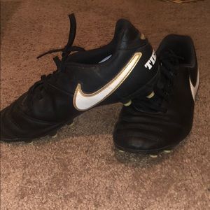 Black Nike cleats with gold outline white swoosh